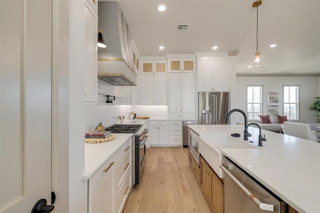 kitchen with light stone counters, white cabinets, hanging light fixtures, and premium appliances