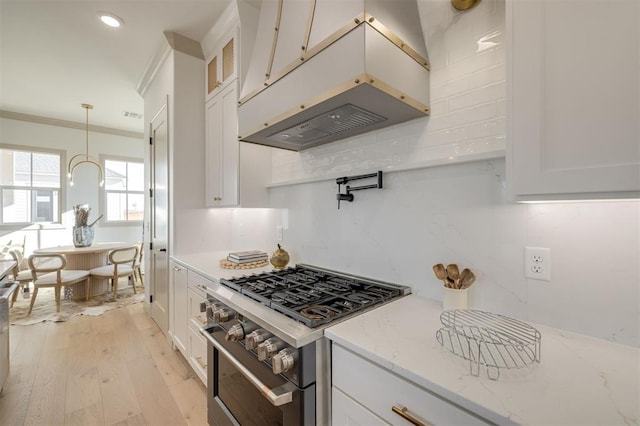 kitchen featuring high end range, custom range hood, and white cabinetry