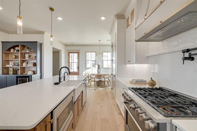 kitchen with premium range hood, hanging light fixtures, decorative backsplash, an island with sink, and white cabinetry