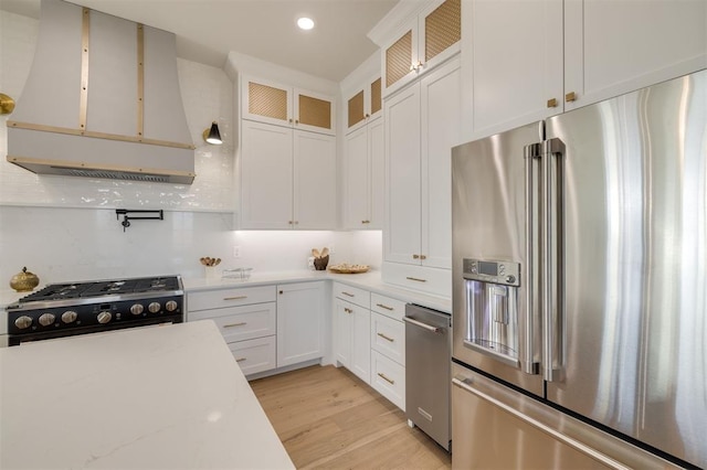 kitchen with decorative backsplash, premium appliances, light hardwood / wood-style floors, and white cabinetry