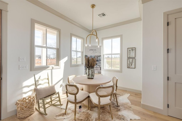 dining space with light hardwood / wood-style flooring and ornamental molding