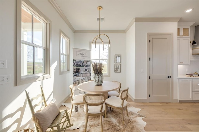 dining space with light hardwood / wood-style floors and crown molding