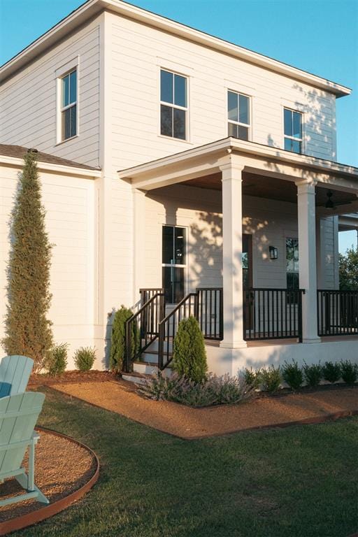 back of house featuring a lawn and covered porch