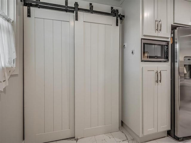 kitchen with appliances with stainless steel finishes, a barn door, and white cabinetry