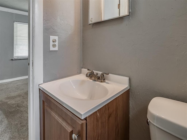 bathroom with vanity, toilet, and crown molding