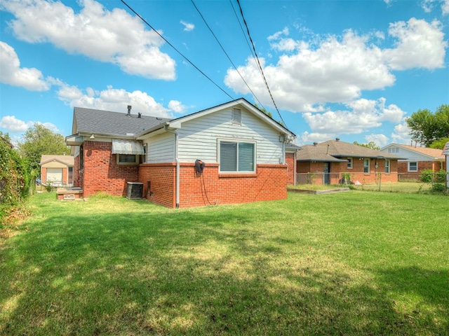 rear view of house with a lawn and central AC