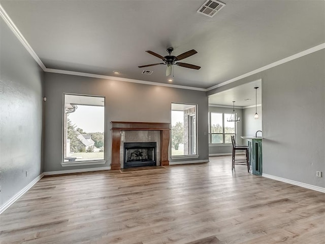 unfurnished living room featuring crown molding, a fireplace, ceiling fan with notable chandelier, and hardwood / wood-style flooring