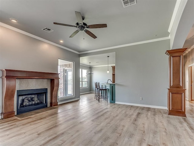 unfurnished living room with ceiling fan, sink, light hardwood / wood-style flooring, crown molding, and a fireplace