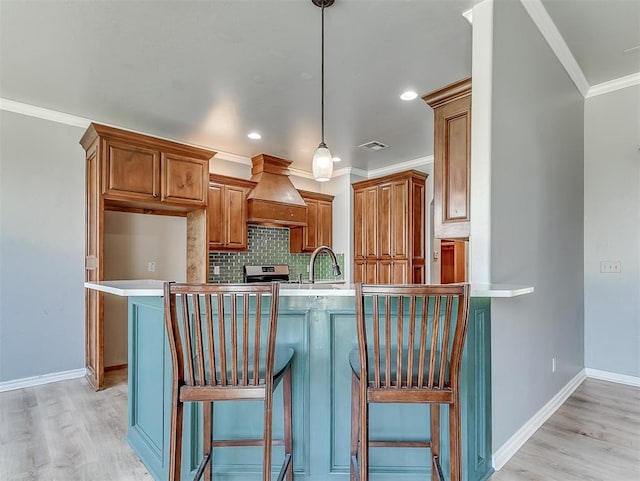 kitchen with a breakfast bar area, kitchen peninsula, light hardwood / wood-style flooring, and custom exhaust hood