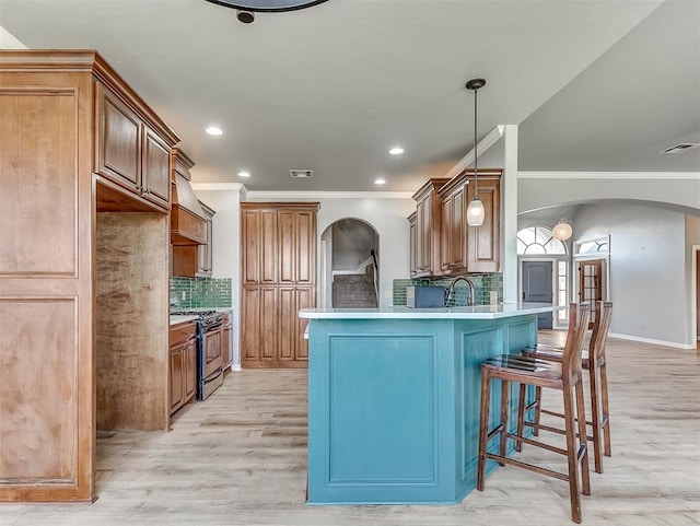 kitchen with backsplash, crown molding, light wood-type flooring, gas stove, and kitchen peninsula