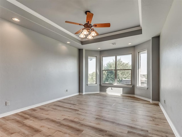 spare room with a tray ceiling, crown molding, ceiling fan, and light hardwood / wood-style floors