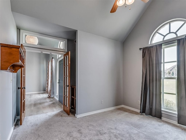 carpeted empty room featuring high vaulted ceiling, ceiling fan, and a healthy amount of sunlight