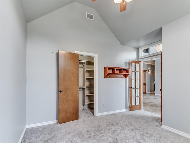 unfurnished bedroom with french doors, high vaulted ceiling, a walk in closet, light carpet, and a closet