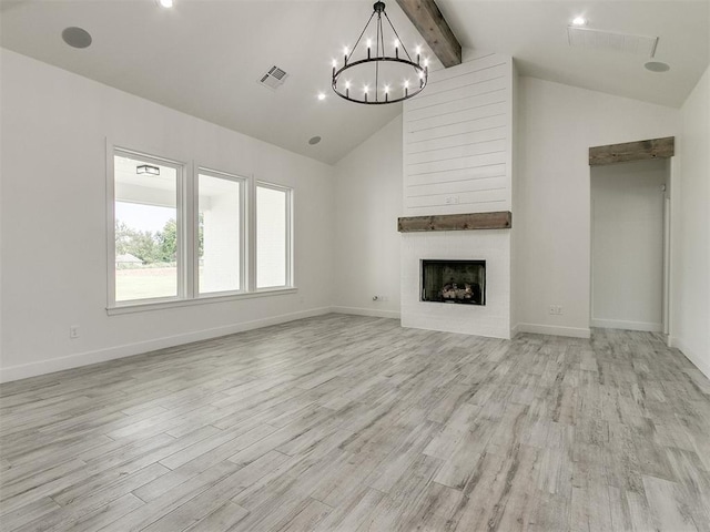 unfurnished living room with a notable chandelier, beam ceiling, a large fireplace, and light wood-type flooring