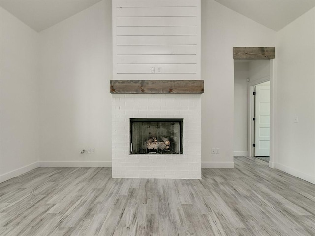 unfurnished living room featuring light hardwood / wood-style flooring, a fireplace, and vaulted ceiling