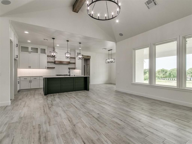 kitchen featuring hanging light fixtures, white cabinetry, a kitchen island with sink, and tasteful backsplash