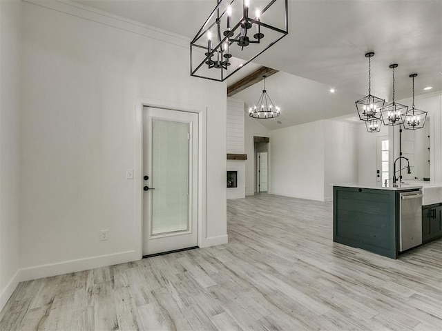 kitchen featuring pendant lighting, an island with sink, a large fireplace, stainless steel dishwasher, and light hardwood / wood-style floors