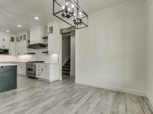 kitchen with built in microwave, high end stainless steel range, white cabinetry, pendant lighting, and backsplash