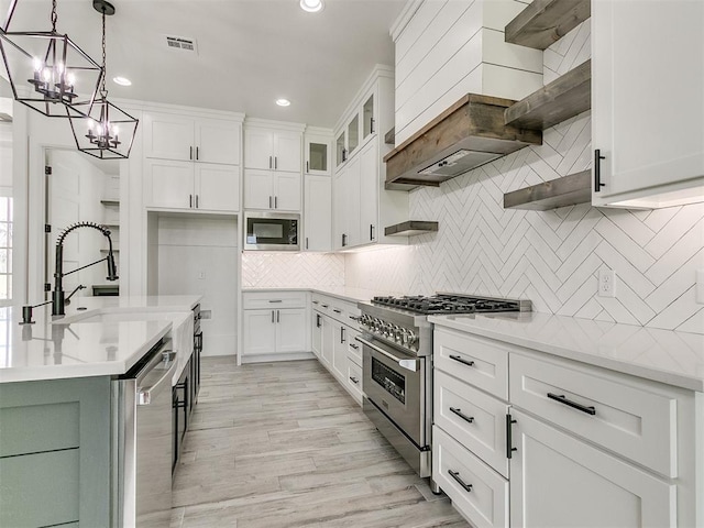 kitchen featuring pendant lighting, light hardwood / wood-style flooring, appliances with stainless steel finishes, white cabinetry, and tasteful backsplash