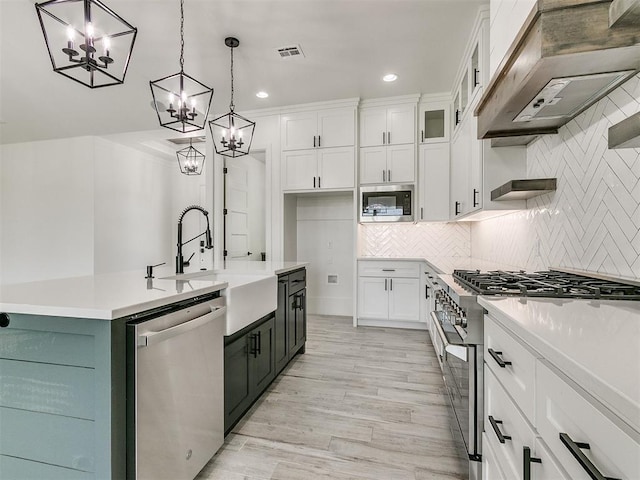 kitchen featuring hanging light fixtures, appliances with stainless steel finishes, custom range hood, and white cabinets