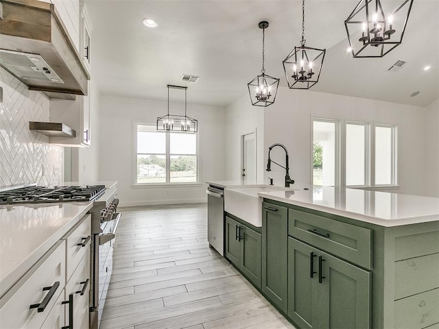 kitchen featuring white cabinetry, stainless steel appliances, sink, and an island with sink