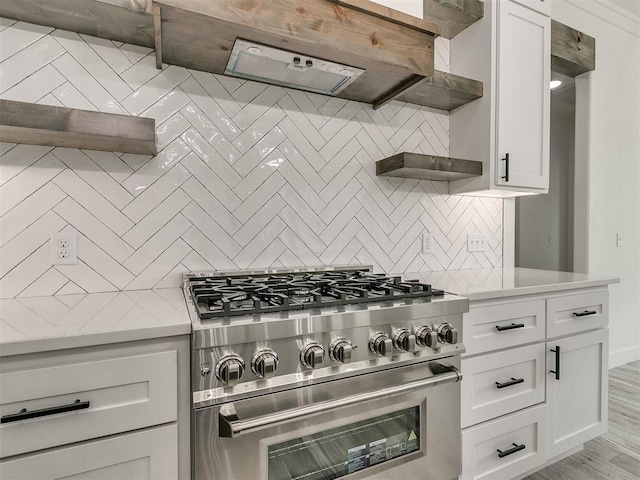 kitchen featuring tasteful backsplash, stainless steel stove, light hardwood / wood-style flooring, and white cabinets