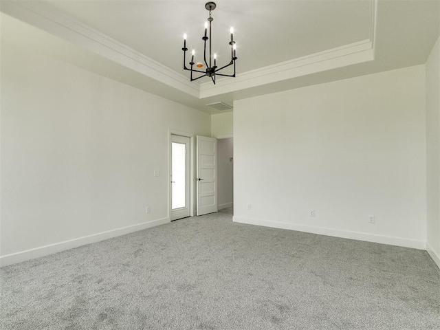 empty room featuring an inviting chandelier, ornamental molding, a tray ceiling, and carpet