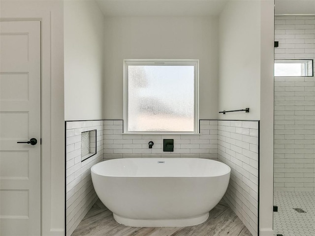 bathroom featuring hardwood / wood-style flooring, plus walk in shower, tile walls, and a wealth of natural light