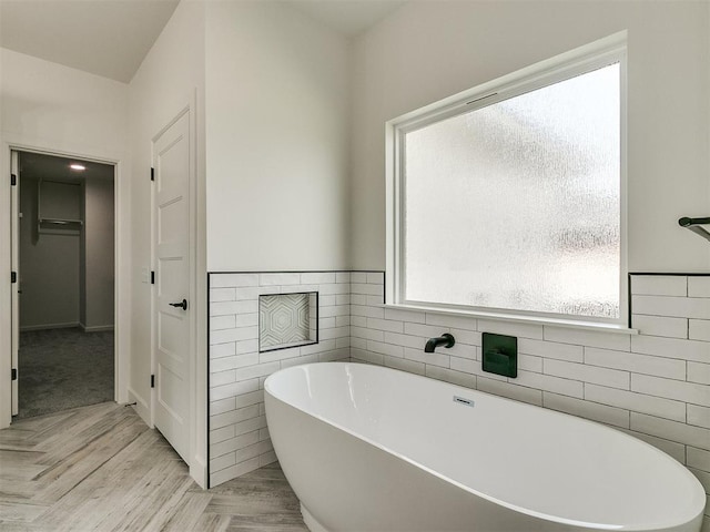 bathroom featuring tile walls and a tub