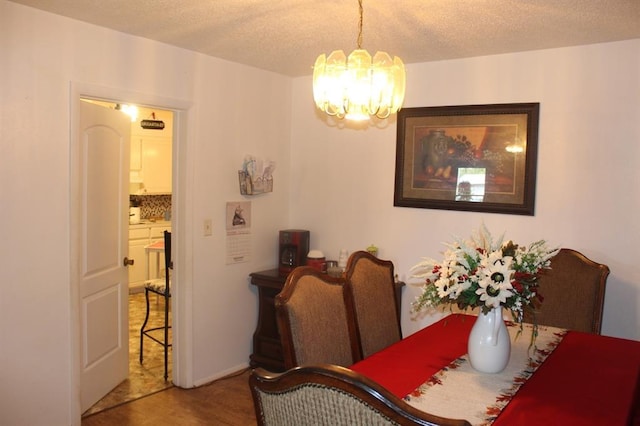 dining area with hardwood / wood-style floors, a chandelier, and a textured ceiling