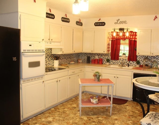 kitchen featuring sink, tasteful backsplash, white cabinetry, and black appliances