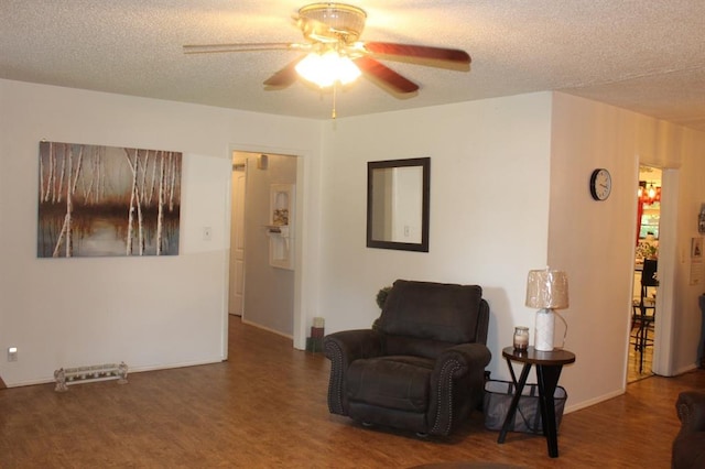 sitting room with a textured ceiling, dark hardwood / wood-style floors, and ceiling fan