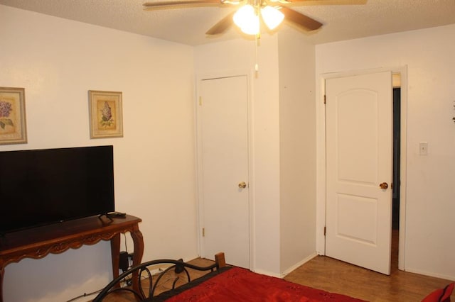 bedroom featuring ceiling fan, wood-type flooring, and a textured ceiling