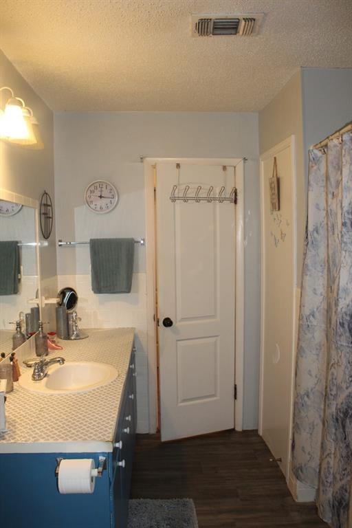 bathroom with vanity, wood-type flooring, and a textured ceiling