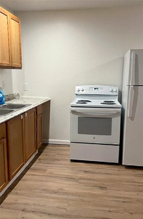 kitchen featuring white range with electric cooktop, light hardwood / wood-style flooring, fridge, and sink