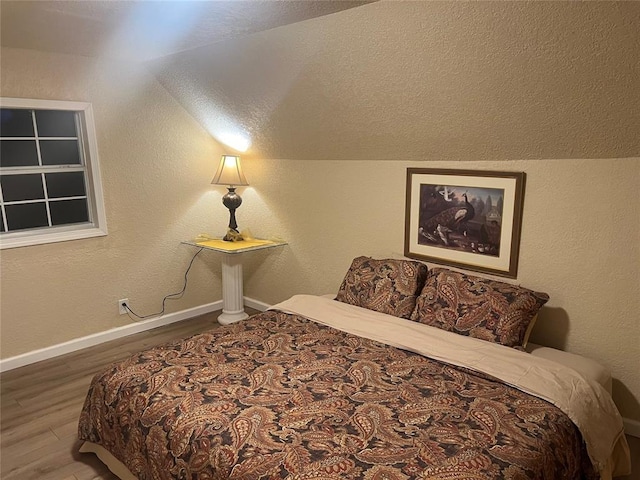 bedroom with wood-type flooring and lofted ceiling