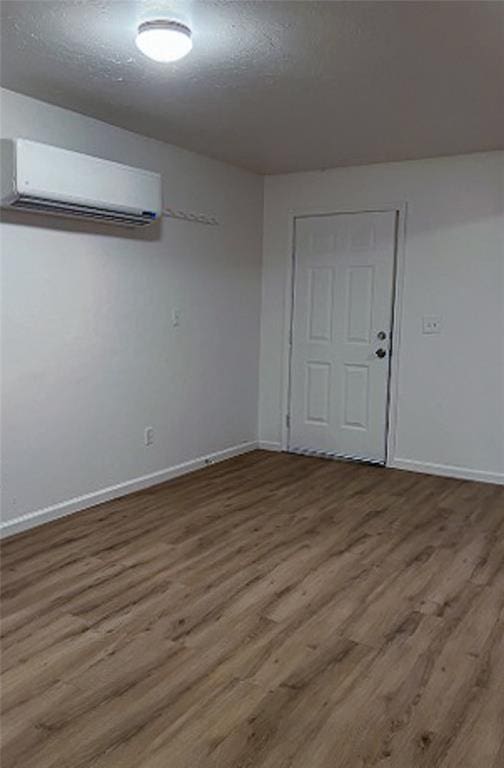 empty room with a wall mounted air conditioner, wood-type flooring, and a textured ceiling