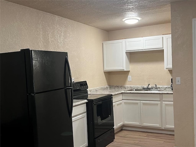 kitchen with black appliances, white cabinets, sink, light hardwood / wood-style flooring, and light stone counters