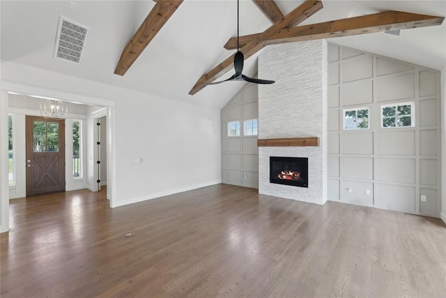 unfurnished living room with hardwood / wood-style flooring, a fireplace, beamed ceiling, and high vaulted ceiling