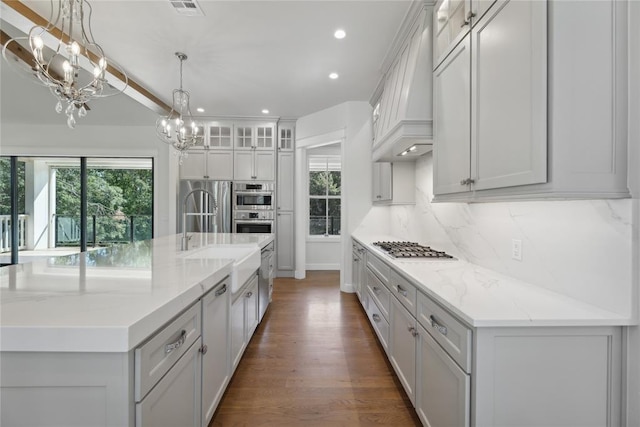 kitchen with a spacious island, sink, decorative light fixtures, dark hardwood / wood-style flooring, and a chandelier