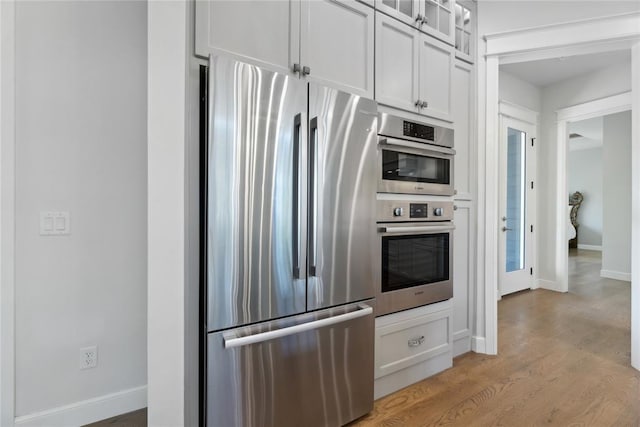 kitchen with light hardwood / wood-style floors, white cabinetry, and appliances with stainless steel finishes