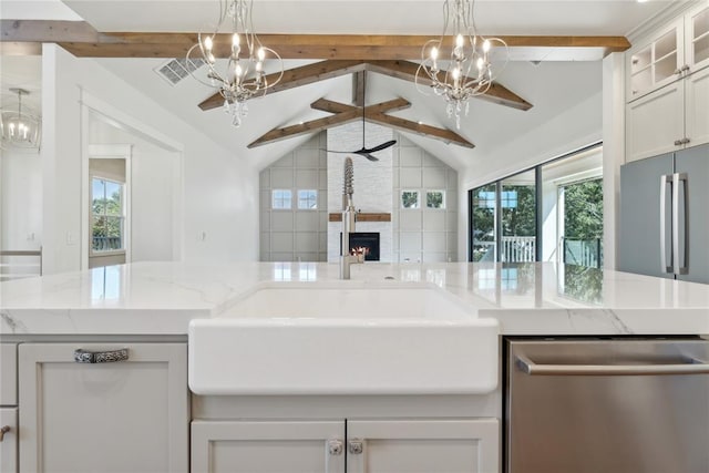 kitchen with vaulted ceiling with beams, white cabinetry, a healthy amount of sunlight, and a stone fireplace