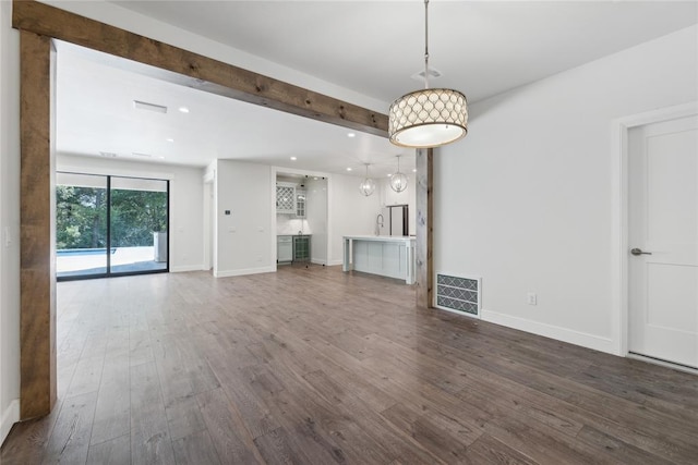 unfurnished living room featuring beam ceiling and dark wood-type flooring