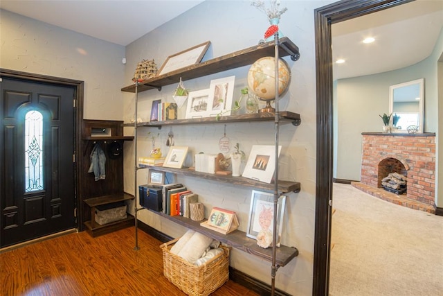 foyer entrance featuring hardwood / wood-style flooring and a brick fireplace