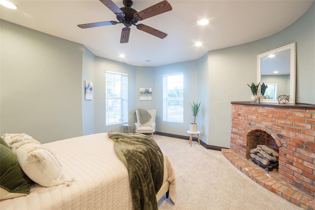 bedroom with ceiling fan, light carpet, and a fireplace