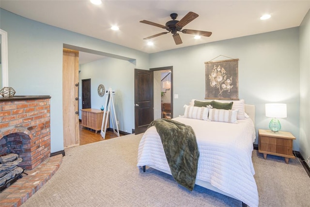 bedroom featuring ceiling fan, a fireplace, and carpet floors