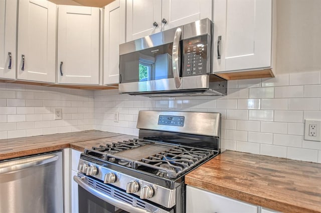 kitchen featuring appliances with stainless steel finishes, backsplash, butcher block countertops, and white cabinetry