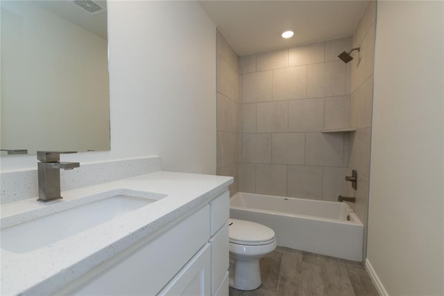 full bathroom featuring vanity, wood-type flooring, tiled shower / bath combo, and toilet