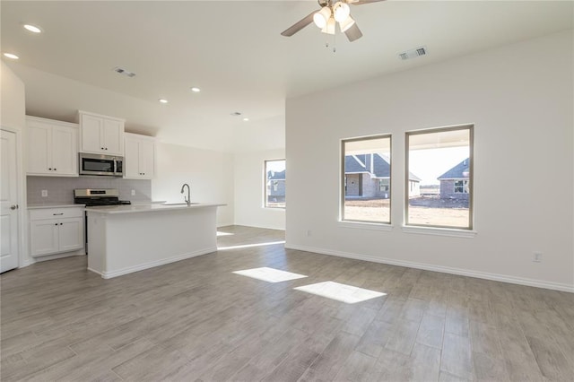 kitchen with a kitchen island with sink, white cabinets, light hardwood / wood-style floors, and appliances with stainless steel finishes