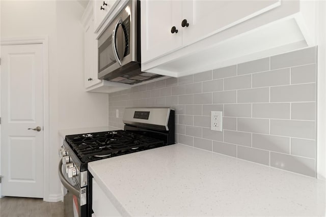 kitchen with tasteful backsplash, light stone countertops, white cabinets, and appliances with stainless steel finishes